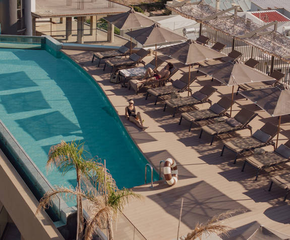 A Woman Sunbathing on the Side of the Pool Wide View