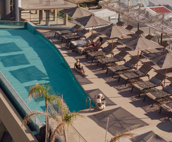 A Woman Sunbathing on the Side of the Pool Wide View