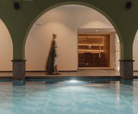 A Woman Walking in The Relaxation Area of the Spa by the Interior Pool