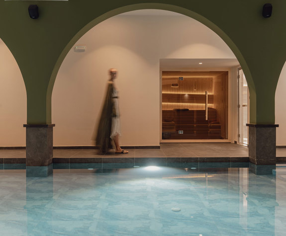 A Woman Walking in The Relaxation Area of the Spa by the Interior Pool