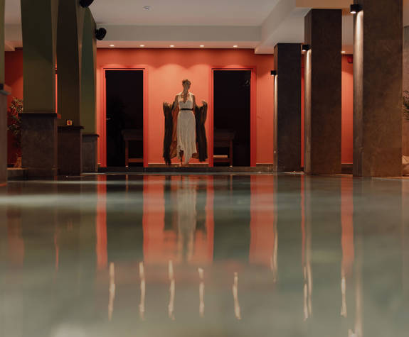 A Woman Standing in front of the Interior Pool of the Spa Relaxation Area