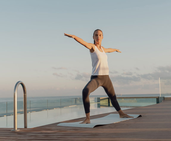 A Woman doing Yoga Exercises By the Pool