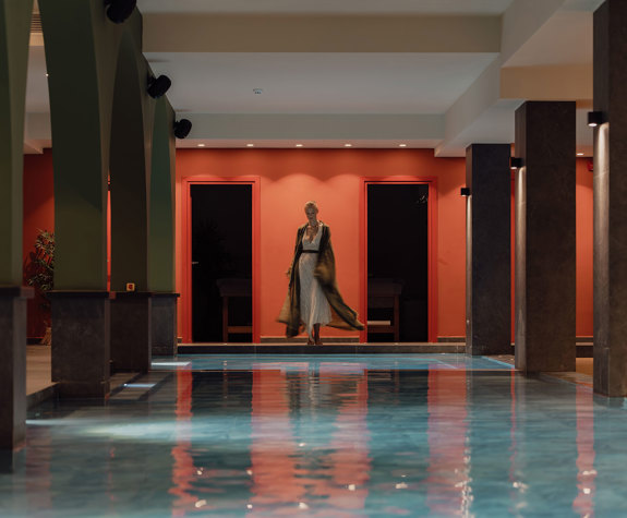 A Woman Standing in front of the Interior Pool of the Spa Relaxation Area