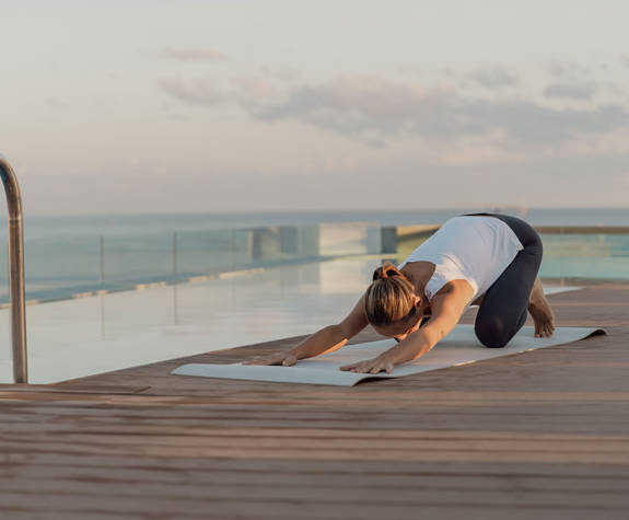A Woman doing Yoga Exercises By the Pool