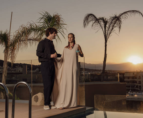 A Couple Enjoying their Drinks Standing by the Pool at Sunset