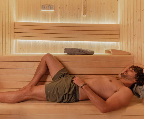 A Man Relaxes Laying in the Sauna Room