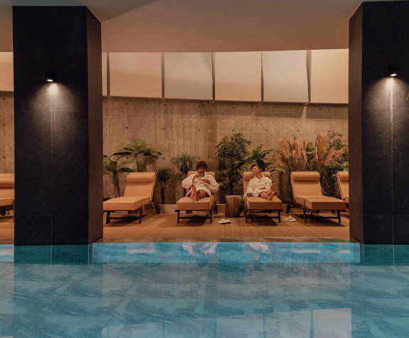 A Couple Relaxing in the Spa Area on the Folding Chairs beside the Interior Pool