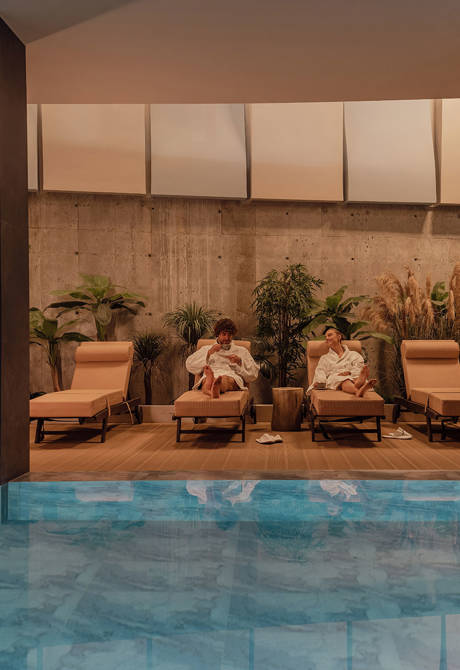 A Couple Relaxing in the Spa Area on the Folding Chairs beside the Interior Pool